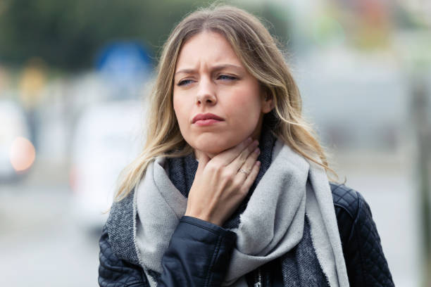 jeune femme de la maladie avec la douleur de gorge terrible marchant dans la rue. - gorge cou photos et images de collection