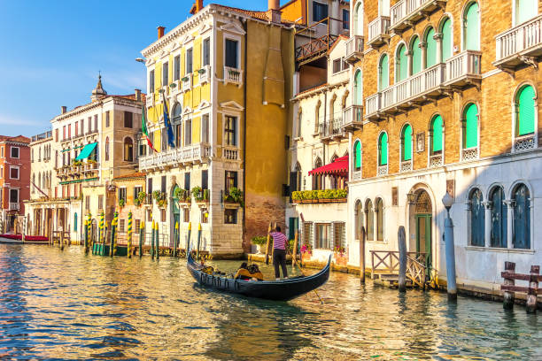 a gondolier in his gondola in the grand canal of venice in front of old palaces - men gondolier people activity imagens e fotografias de stock