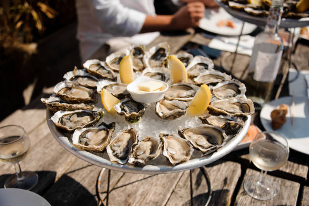 Tasty oysters on the plate on the table Tasty oysters on the half shell served flat lay on wooden background directly above view restaurant france stock pictures, royalty-free photos & images
