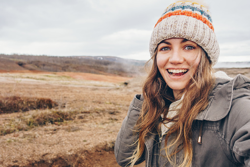 Young happy woman traveler taking selfie portrait in Icelandic landscape