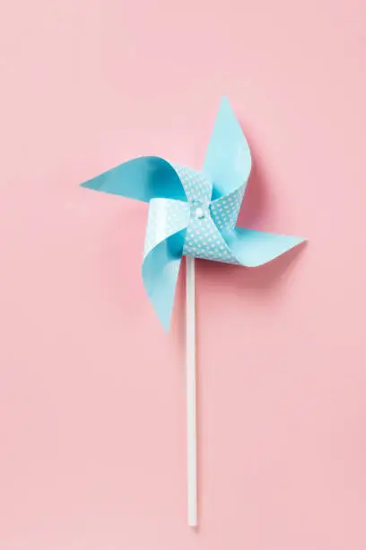 Photo of Blue paper pinweel on pink background. Energy ecological concept