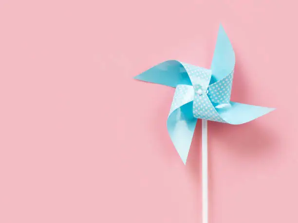 Photo of Blue paper pinweel on pink background. Energy ecological concept