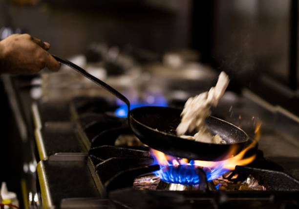 istock Professional Chef Prepares Dish in a Pan with Open Flames 1076833364