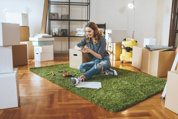 istock Cheerful girl texting while unpacking in her new apartment 1076852272