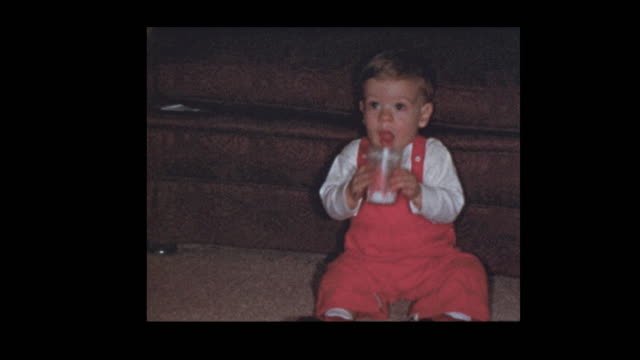 1954 Toddler in red suspenders boy drinks milk from glass
