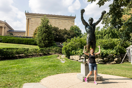 Philadelphia, Pennsylvania. Tourist posing with the Rocky statue, a movie memorial close to the 72 Rocky steps before the entrance of the Philadelphia Museum of Art