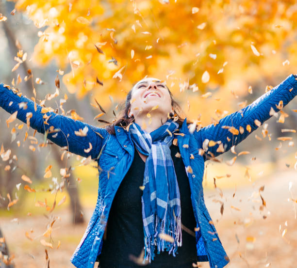 istock A happy woman throwing Autumn leaves 1076886964