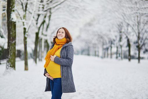Beautiful pregnant woman on her last weeks of pregnancy walking in Paris on a day with heavy snow
