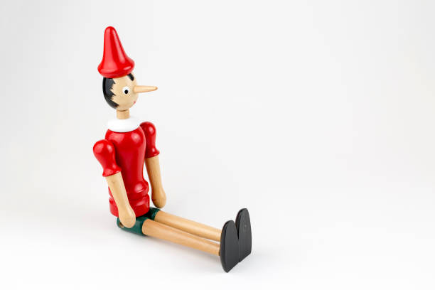 istock Wooden Pinocchio doll sitting isolated on white background. 1076911196