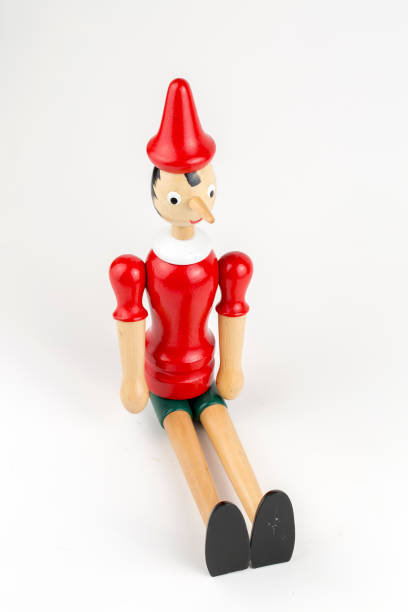 istock Wooden Pinocchio doll sitting isolated on white background. 1076911206