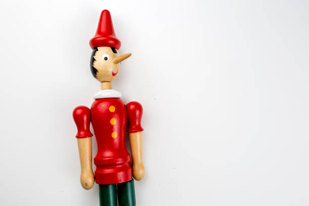 istock Wooden Pinocchio doll sitting isolated on white background. 1076911220