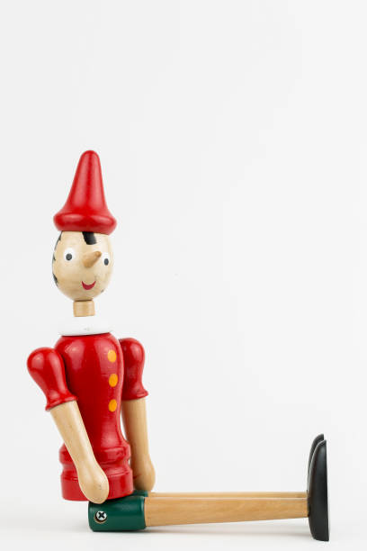 istock Wooden Pinocchio doll sitting isolated on white background. 1076911282