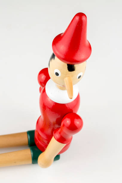 istock Wooden Pinocchio doll sitting isolated on white background. 1076911306