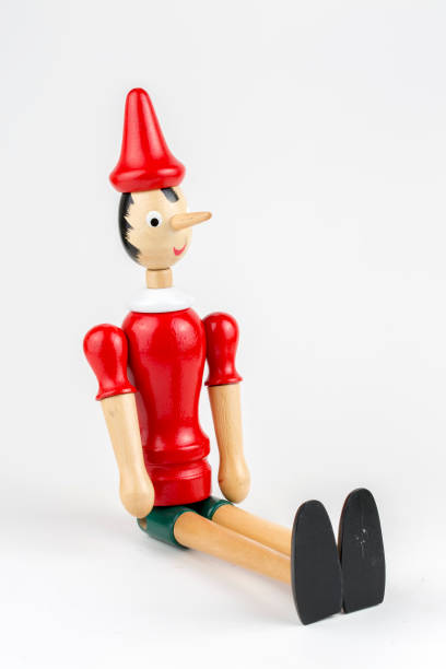 istock Wooden Pinocchio doll sitting isolated on white background. 1076911308