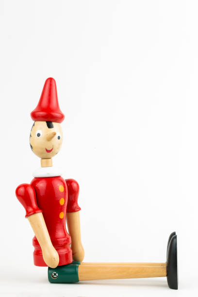 istock Wooden Pinocchio doll sitting isolated on white background. 1076911344