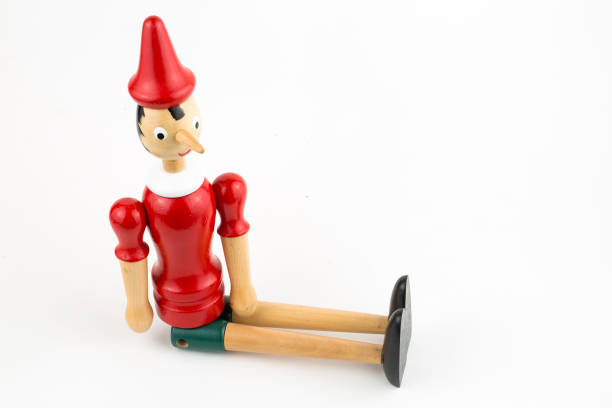 istock Wooden Pinocchio doll sitting isolated on white background. 1076911346