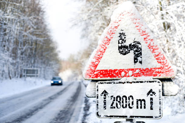 istock Winter road conditions, approaching car, traffic sign 1076923648