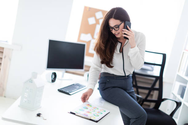istock The young girl sat down on the table, talking on the phone and watching the graphics. 1076945962