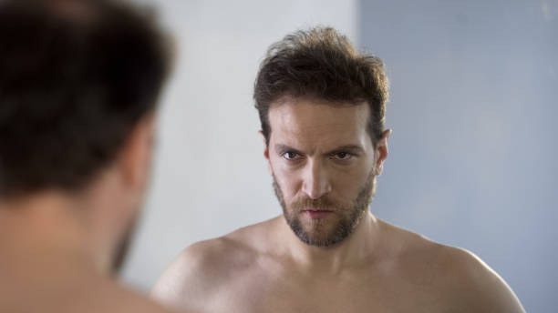 istock Man looking at his mirror reflection with hatred and shame, feeling guilty 1076946782