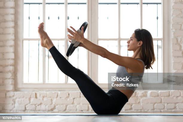 Young Woman Practicing Yoga Paripurna Navasana Exercise With A Ring Stock Photo - Download Image Now