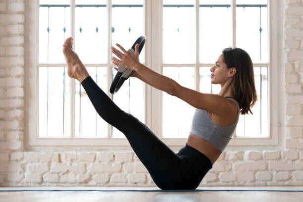 exercício de paripurna navasana praticando ioga de mulher jovem, com um anel - pilates - fotografias e filmes do acervo