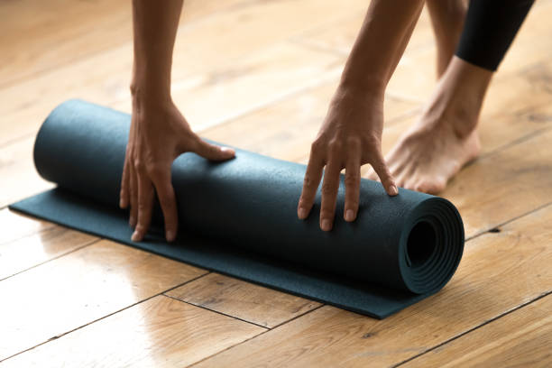 donna che inizia la sua pratica e srotolando il tappetino per esercizi di fitness blu - unrolling foto e immagini stock
