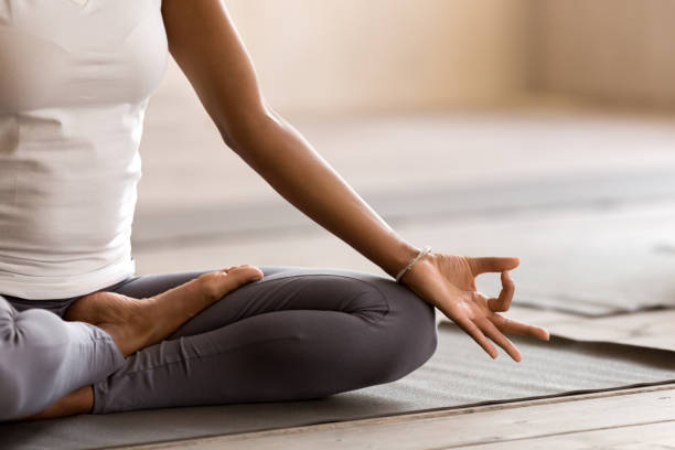 yogi czarna kobieta praktykuje lekcję jogi, wykonując ćwiczenia ardha padmasana - sitting pose zdjęcia i obrazy z banku zdjęć