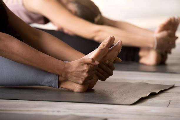 요가, paschimottanasana 포즈를 연습 하는 여자의 그룹을 닫습니다. - bikram yoga pilates beautiful 뉴스 사진 이미지