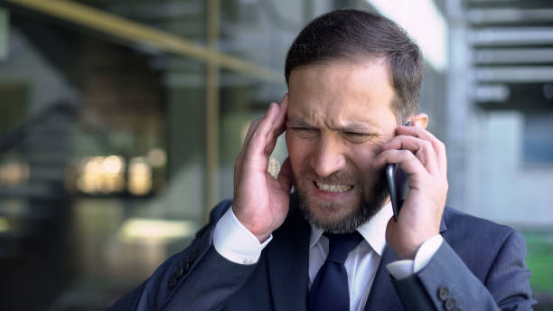 istock Overworked male manager talking on phone, suffering from migraine, headache 1076949746