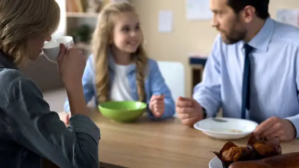 Happy family sitting at kitchen desk and having breakfast, morning ritual