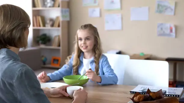 Cheerful daughter and mother having pleasant breakfast together, morning