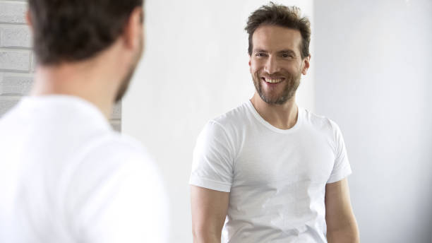 istock Cheerful man looking at reflection in mirror, motivating for success during day 1076950440