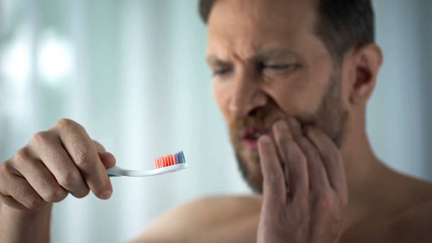 maschio in bagno che guarda lo spazzolino del sangue, l'igiene orale, la malattia da parodontosi - dental hygiene human teeth toothbrush brushing teeth foto e immagini stock