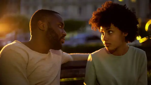 Afro-american lady looking at boyfriend with hope, misunderstanding, conflict