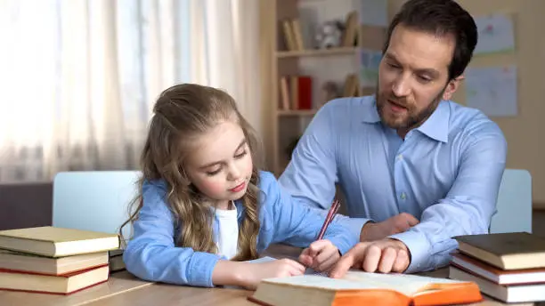 Strict teacher helping little girl to do homework and learn new words, education