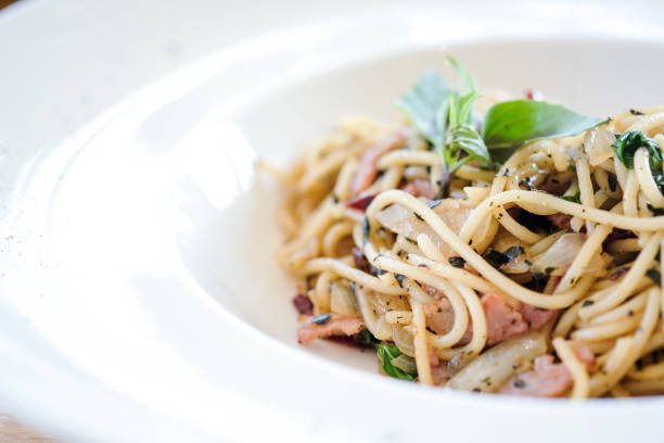 Woman hand holding a plate of spaghetti on a green wall.