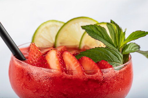 Frozen strawberry margarita cocktail in margarita glass isolated on white