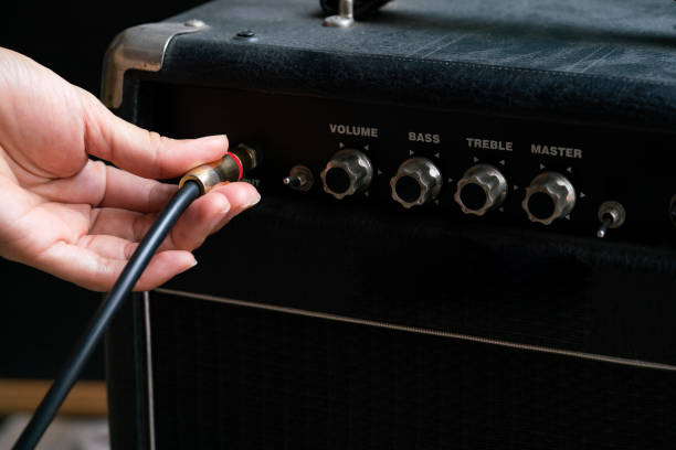 istock woman hand plugging cable into the amplifier guitar, music concept 1076961812