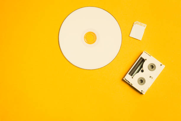 istock Compact disc and memory card on yellow background. digital video cassette. copy space 1076964352
