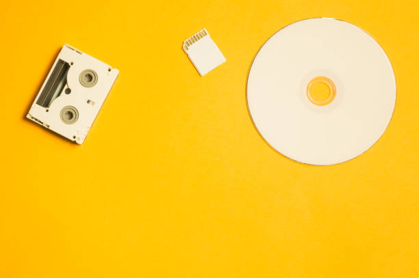 istock Compact disc and memory card on yellow background. digital video cassette. copy space 1076967180