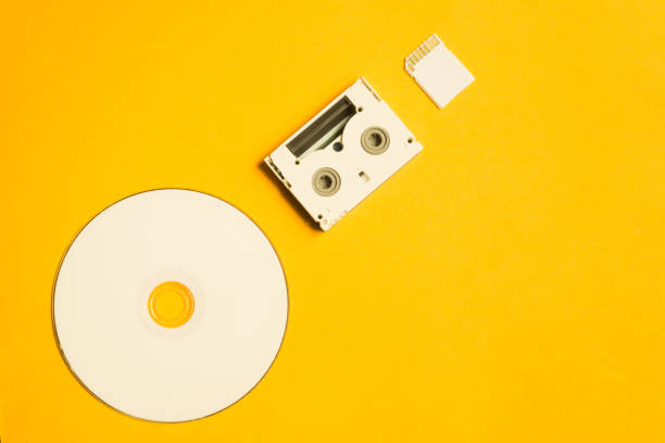istock Compact disc and memory card on yellow background. digital video cassette. copy space 1076967260