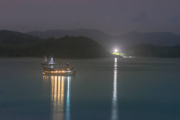 istock light and boat in sea at midnight time 1076983410