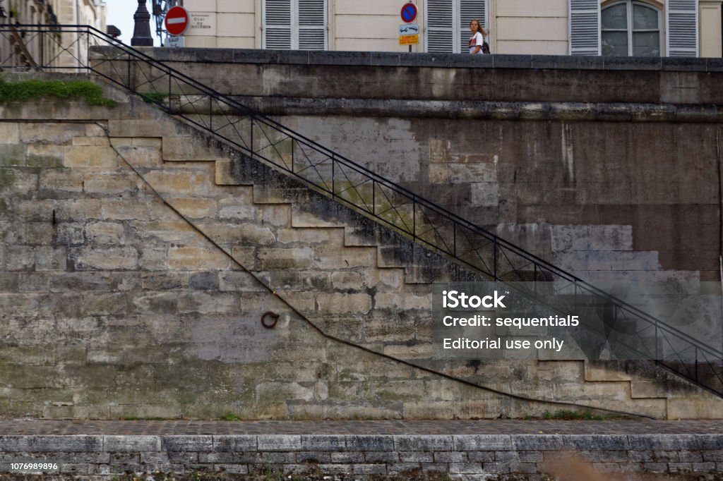 Steps from the the Seine Paris - August 3, 2017: Steps leading up from the Seine River to the street above where a woman walks by. Adult Stock Photo
