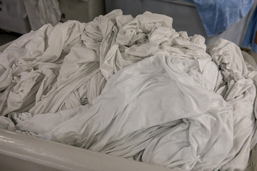 A large industrial size laundry bin is filled with dirty sheets. Shot with Canon 5D Mark lV.