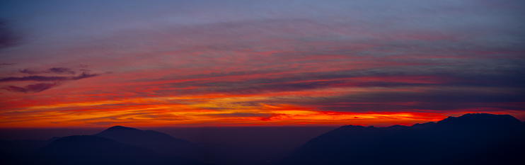 Fiery sunset from mountain peak in a cloudy evening. Fall season. Orobie mountains. Italian Alps