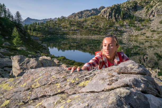istock Female climber reaching mountain top; lake view 1077023082
