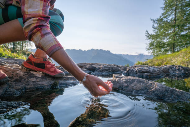 main de l’homme incurvé pour attraper l’eau douce du lac de montagne, suisse - spring ride photos et images de collection