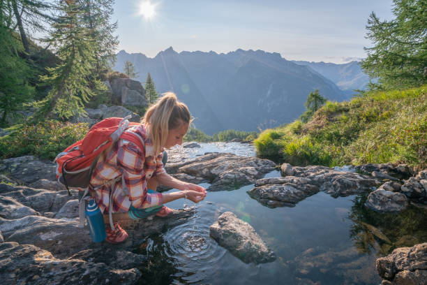 Young woman hiker on trail in Summer refreshing from water riverShot in Switzerland People travel outdoor concept