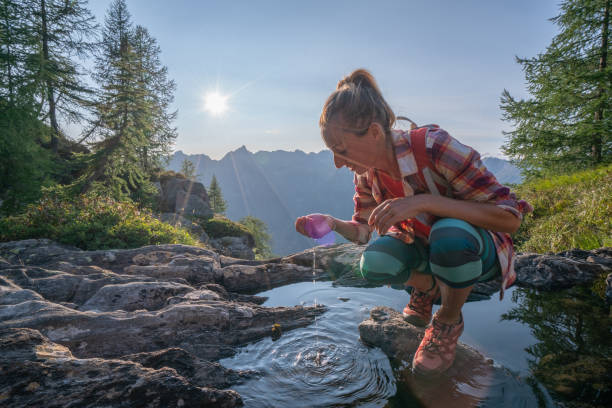 istock Hiker female drinking water on mountain trail from fresh stream 1077026462