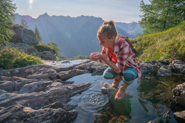 istock Hiker female drinking water on mountain trail from fresh stream 1077026572